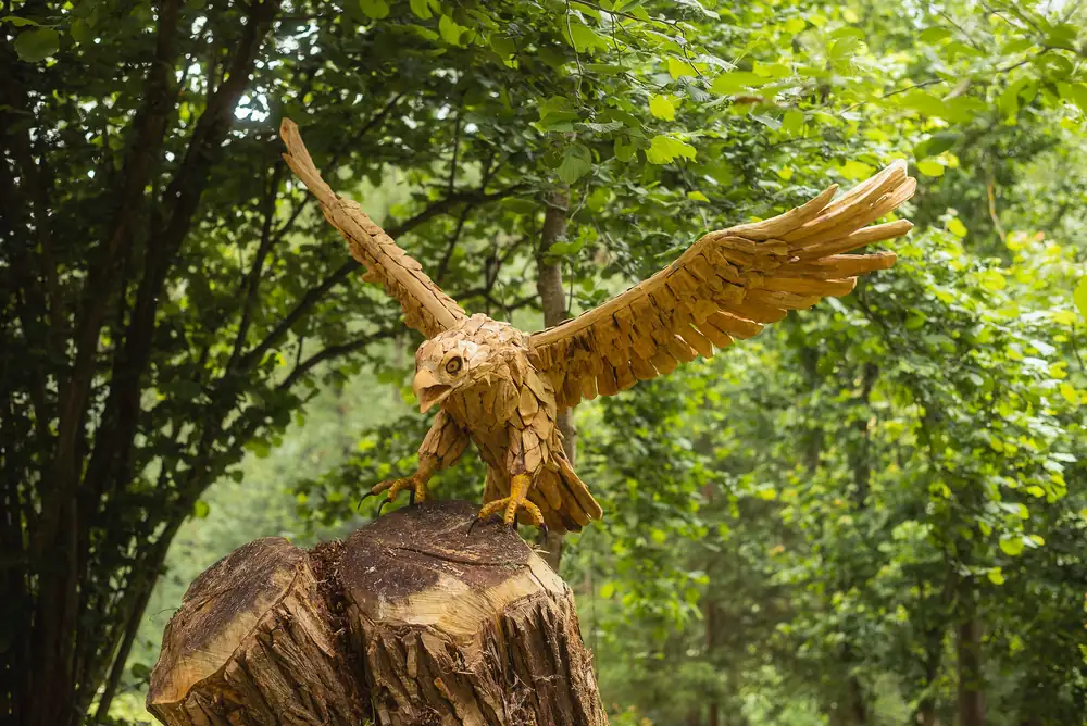 Drevený orol pristáva na pni s rozprestretými krídlami