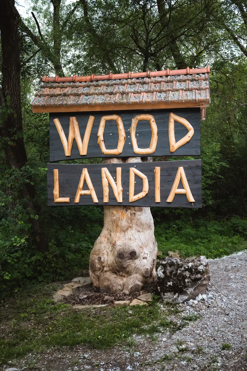 Drevená tabuľa s nápisom Woodlandia pri vjazde do areálu